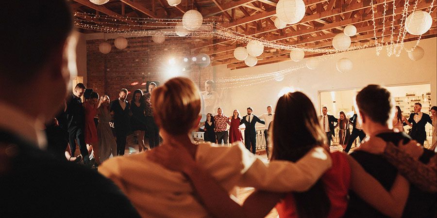 Goście weselni tańczący i śpiewający w kółku.