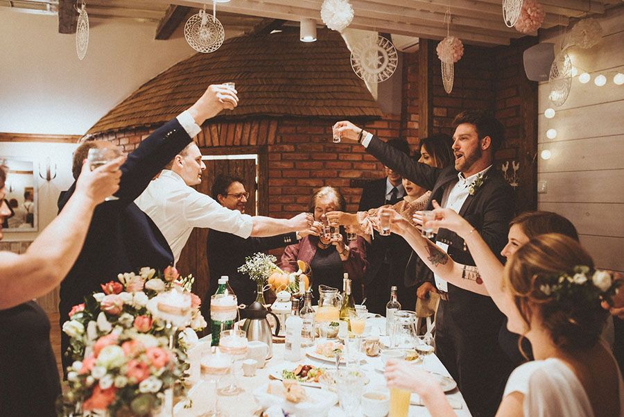 Goście wznoszący toast przy stole, pozwalający, by to DJ zdecydował, jaka jest najlepsza muzyka na ich wesele.